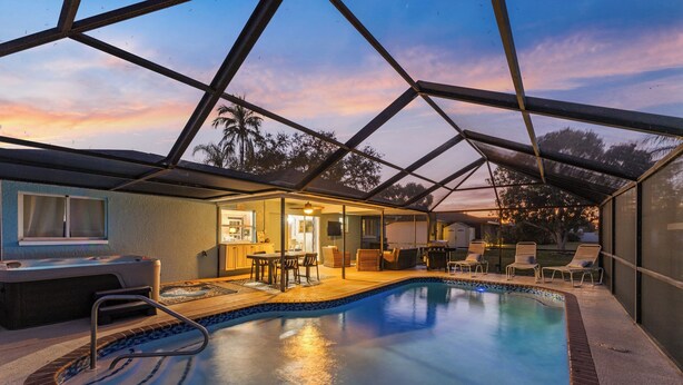 Ein Schwimmbad mit Glasdach, Liegestühlen und einem Whirlpool.