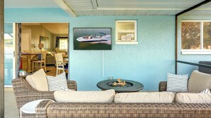 Ein gemütliches Zimmer mit einer Korbschaumsofa, einem kleinen runden Tisch mit Feuerstelle und einem an der Wand befestigten Fernseher.