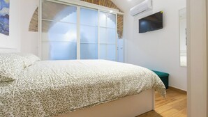 A bedroom with a bed, a sliding glass door, an air conditioning unit, and a television. - Two steps from theColosseum brand new apartment with maximum comfort for family (Roma)