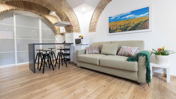 A modern living room with a sofa, a coffee table, and a painting of a sunflower field. - Two steps from theColosseum brand new apartment with maximum comfort for family (Roma)