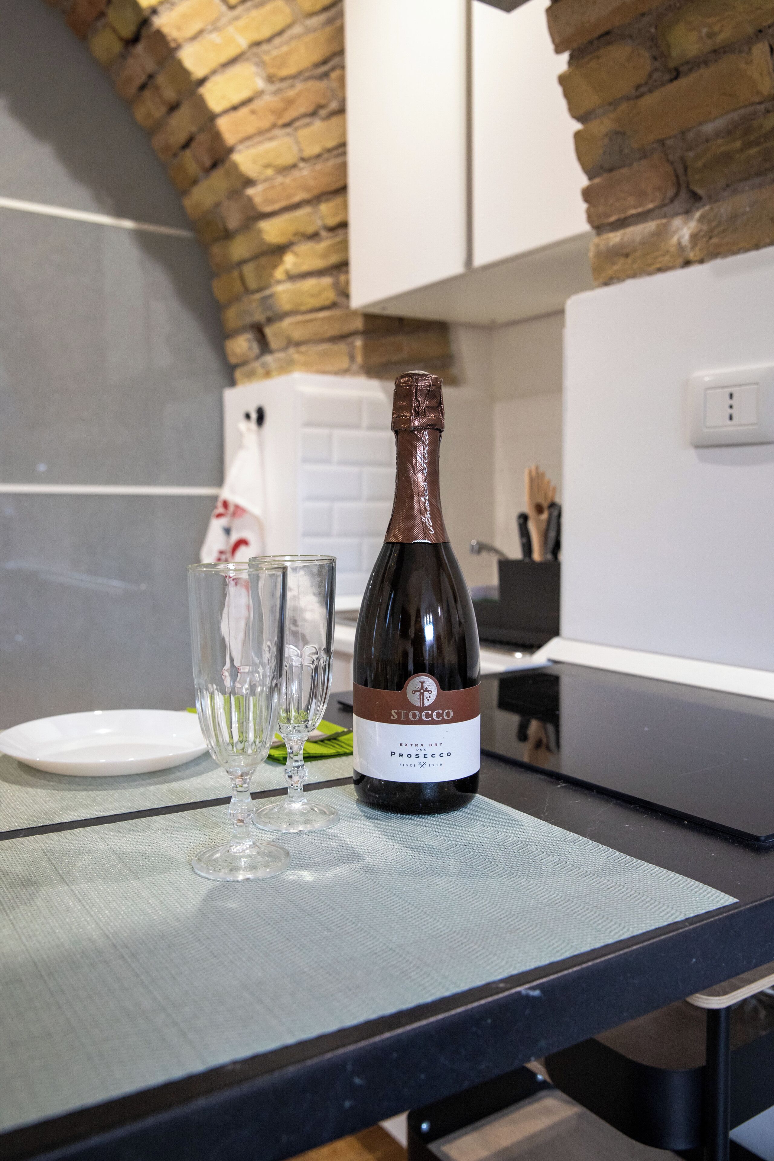 A bottle of Stocco Prosecco on a kitchen counter with two glasses.