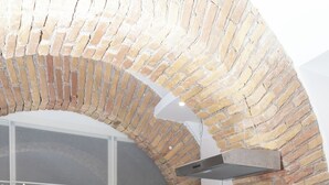 A modern kitchen with a brick arch, a black countertop, three stools, and white cabinetry. - Two steps from theColosseum brand new apartment with maximum comfort for family (Roma)