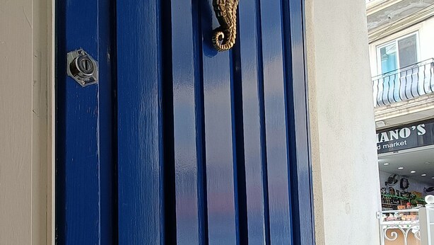 Eine blaue Tür mit einer Messing-Klopfer und einem Schlüsselloch.