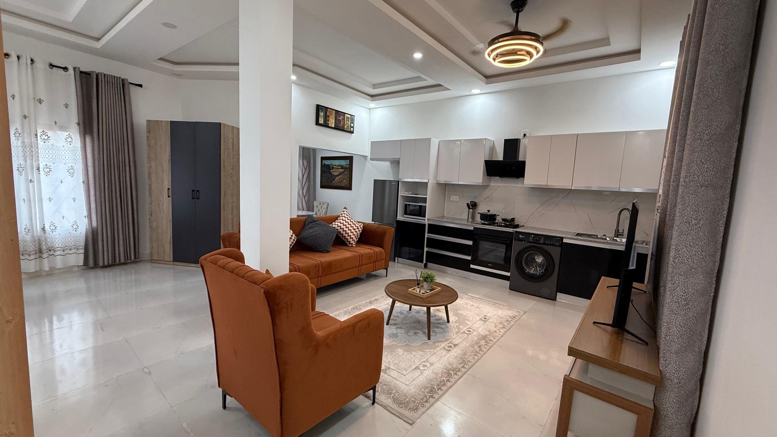 A modern living room with a sofa, a coffee table, and a kitchen area with cabinets and appliances.