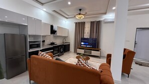 A modern kitchen with a built-in oven, a refrigerator, and a dining area with a sofa and chairs.