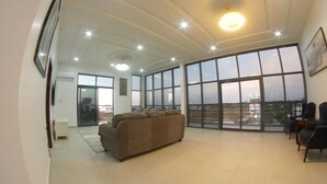 Een ruime woonkamer met een groot raam, een bank en uitzicht op de stad.