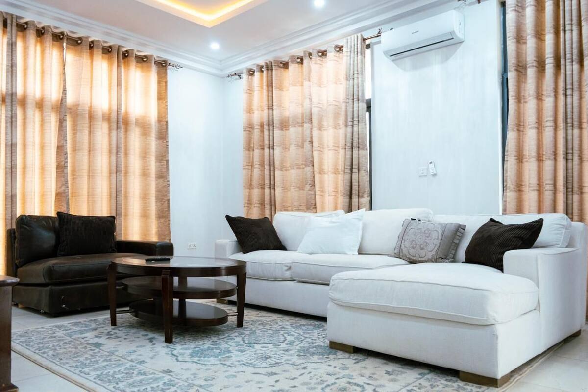 Un salon avec un canapé blanc, un canapé foncé et une petite table ronde.