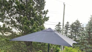 Une terrasse avec une table dressée pour quatre personnes, entourée de chaises, et un grand parasol offrant de l’ombre.