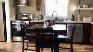 Une cuisine avec un îlot central, une cuisinière, un évier et une fenêtre avec des rideaux.