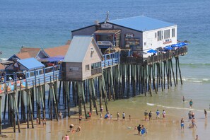 A pier with a restaurant and a bar, extending over the beach.