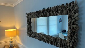 Een kamer met een bijzondere spiegel met houten lijst, een lamp en uitzicht op een bureau met een computer.