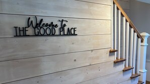 Een houten wand met een bord waarop staat 'Welcome to THE GOOD PLACE'.