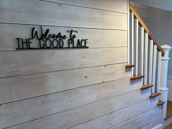A wooden wall with a sign that reads "Welcome to THE GOOD PLACE."