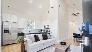 A modern kitchen with white cabinets, stainless steel appliances, and a dining area with a wooden table and chairs. - Cozy/Modern King Suite in Houston Texas (Houston)