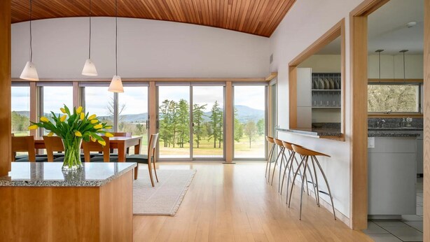 A modern kitchen with a large island, bar seating, and a view of the outdoors. - Contemporary Berkshire Home with Views of Taconic Golf Course (Williamstown)