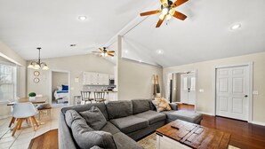A spacious living area with a gray sectional sofa, a wooden coffee table, and a ceiling fan. - Hot Tub/Gameroom/Firepit/ Coler MTB - Downtown (Bentonville)