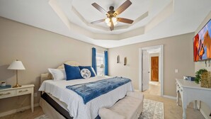 A bedroom with a bed, a ceiling fan, a nightstand, a lamp, a bench, and a painting on the wall. - Hot Tub/Gameroom/Firepit/ Coler MTB - Downtown (Bentonville)