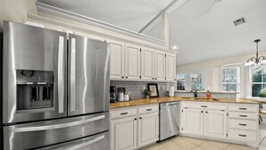 A modern kitchen with stainless steel appliances, white cabinetry, and a granite countertop. - Hot Tub/Gameroom/Firepit/ Coler MTB - Downtown (Bentonville)