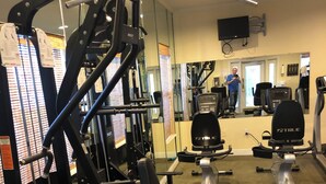 Een sportschool met diverse fitnessapparaten, waaronder een Smith-machine, gewichten en cardio-apparaten.