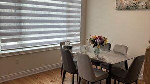 A dining area with a glass table, six chairs, and a vase of flowers. - Dreamland by Wonderland (Vaughan)