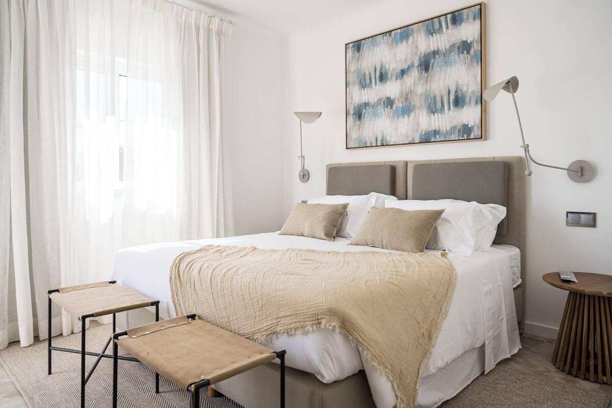 Une chambre à coucher moderne avec un grand lit, deux tables de chevet, une lampe de chevet et un tableau au mur.