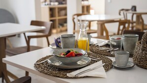 Una mesa de desayuno con un tazón de fruta, un vaso de jugo de naranja y una taza.