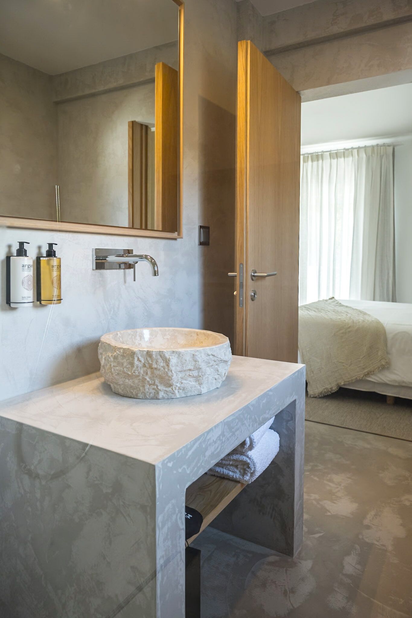 Une salle de bain avec un lavabo en pierre, un miroir et des articles de toilette fixés au mur.