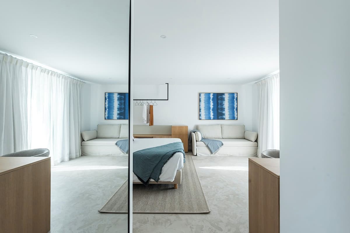 Une chambre d’hôtel moderne avec un grand lit, deux canapés, un bureau et un miroir.