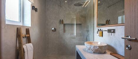 Une salle de bain moderne avec un lavabo en pierre, une douche à parois de verre et une échelle en bois.