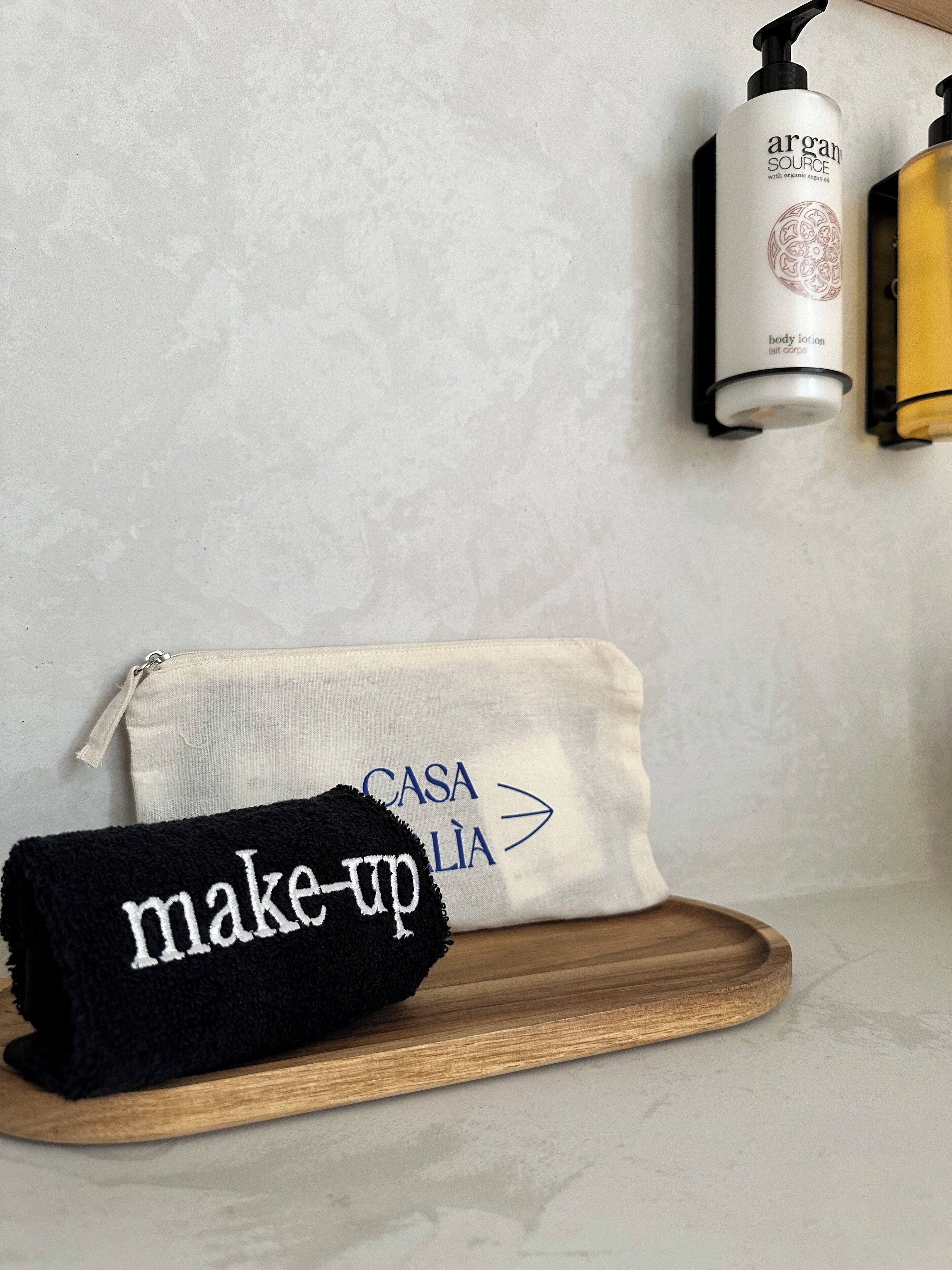Une salle de bain avec une serviette, un masque pour le visage et un flacon de lotion posés sur un comptoir.