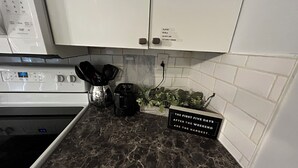 Une cuisine dotée d’un plan de travail en marbre, d’un grille-pain, d’une machine à café et d’un panneau indiquant les cinq premiers jours suivant le week-end.