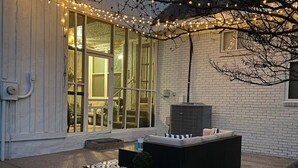 Un patio couvert avec des meubles d’extérieur, des guirlandes lumineuses et une grande fenêtre.