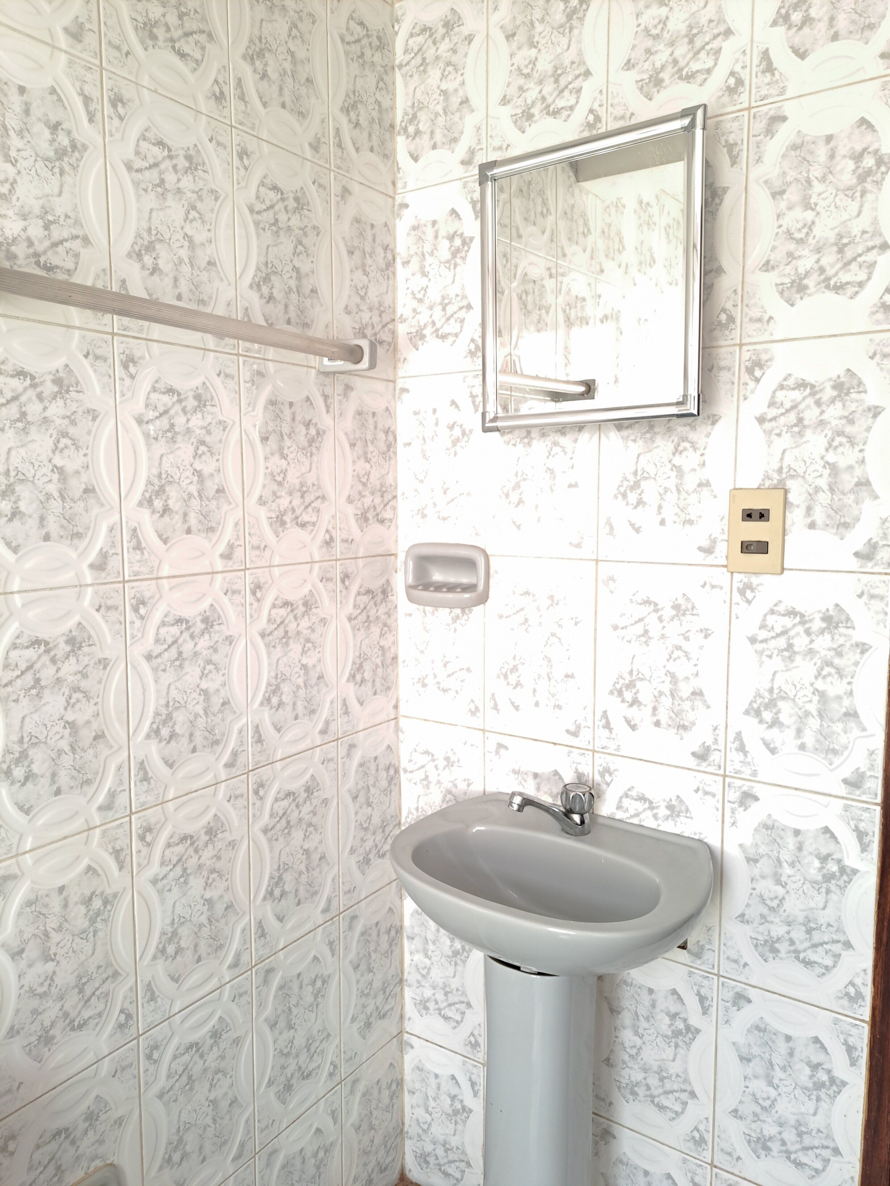 Un baño con lavamanos, espejo y dispensador de jabón.