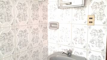 Un baño con lavamanos, espejo y dispensador de jabón.