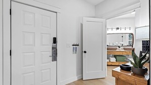 Un interior moderno con una puerta blanca, un banco de madera y un espejo sobre un lavabo.