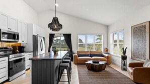 Una cocina moderna con armarios blancos, electrodomésticos de acero inoxidable y una isla central.