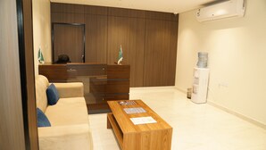 Una sala de estar moderna con un sofá, una mesa de centro de madera, un dispensador de agua y un mueble grande de madera.