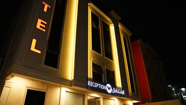 Un hotel con recepción, ventanas amplias y un llamativo letrero que dice 'TEL'.