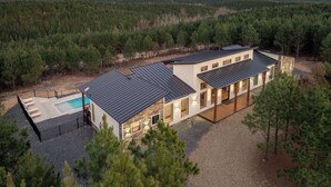 A modern two-story house with a swimming pool, surrounded by a forested area. - Luxury Hilltop, Surreal Views, Pool, Hot Tub, Firepit & 4Kings Bed (Broken Bow)