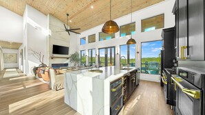 A spacious kitchen with a large island, black appliances, and a view of the outdoors. - Luxury Hilltop, Surreal Views, Pool, Hot Tub, Firepit & 4Kings Bed (Broken Bow)