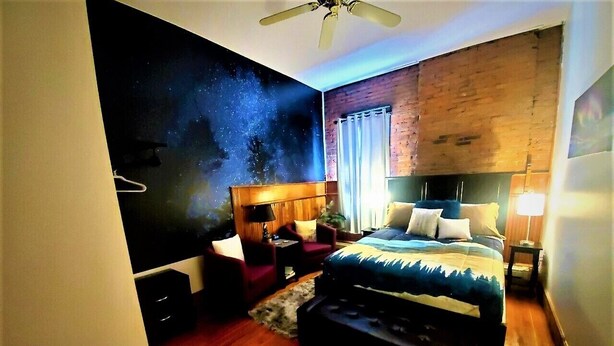 Un dormitorio con un mural de estrellas en la pared, una cama de madera, un escritorio y una silla.