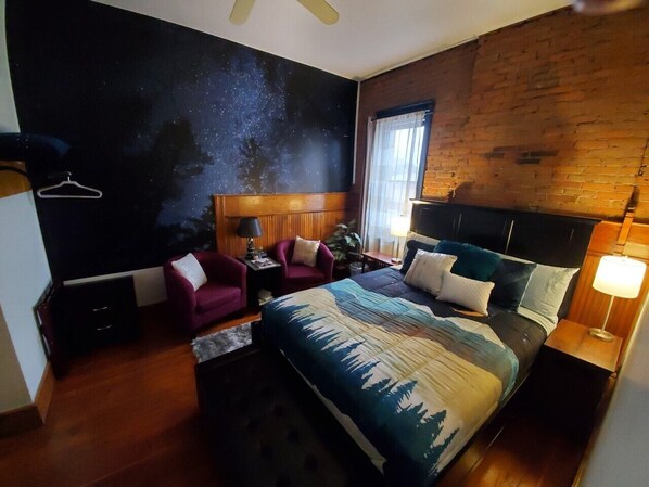 Un dormitorio con una cama grande, una silla, una mesita de noche y una pared con diseño de estrellas.