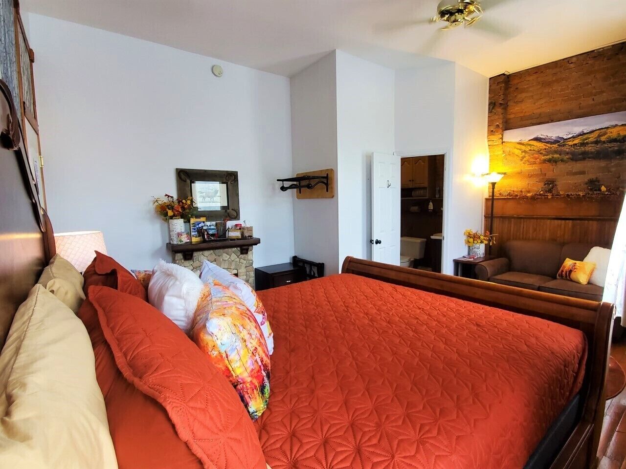 Un dormitorio con una cama grande, cabecera de madera, una mesita de noche, una lámpara y un cuadro en la pared.