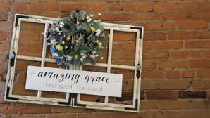 A rustic wall decoration with a sign that reads "amazing grace how sweet the sound" and a floral arrangement. - Aspen Inn - Summer Suite (Creede)