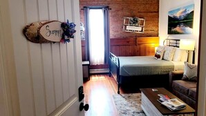 A bedroom with a bed, a nightstand, a dresser, a ceiling fan, and a window with curtains. - Aspen Inn - Summer Suite (Creede)