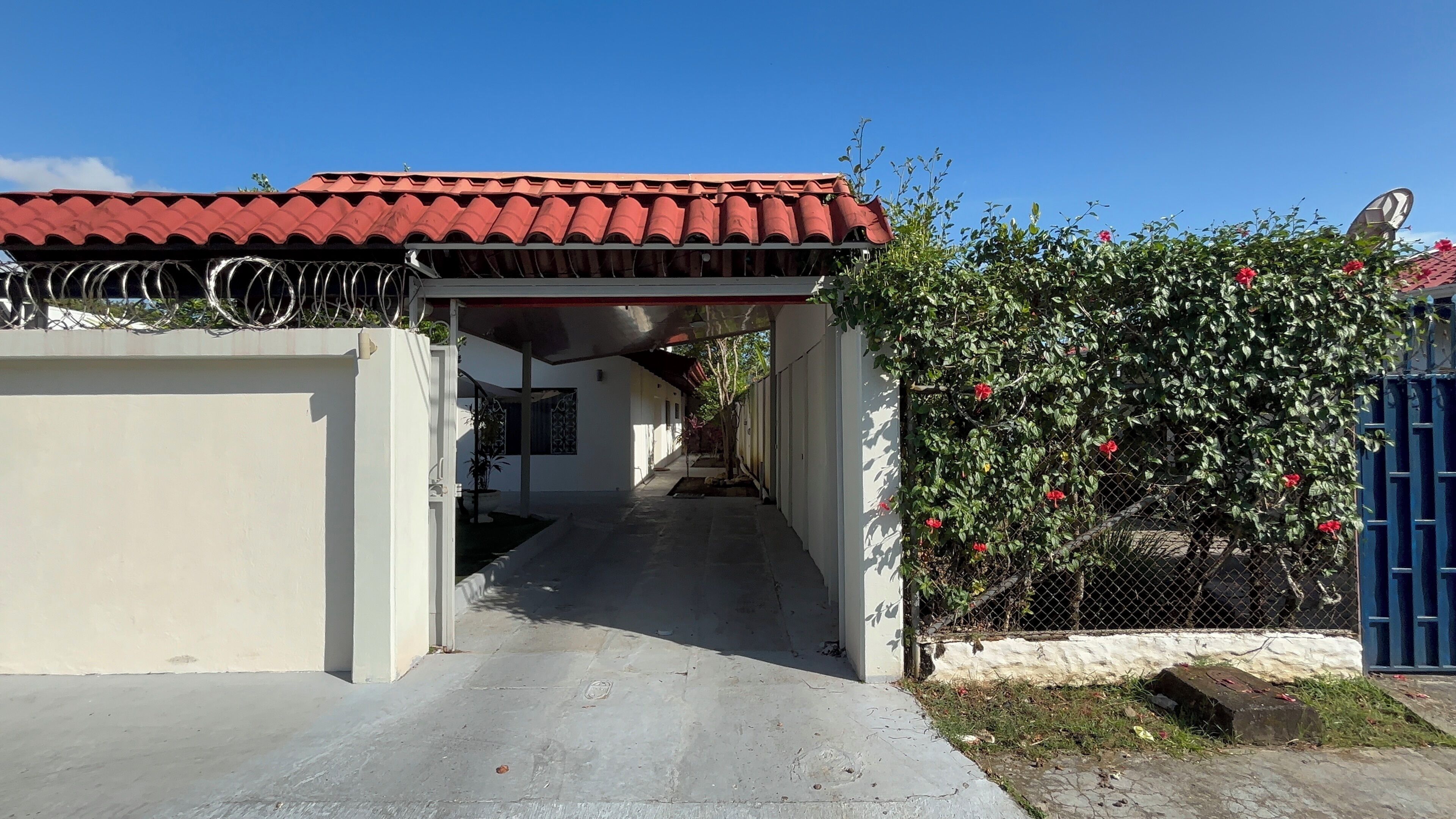 A pathway leading to a building with a red-tiled roof and a covered entrance.