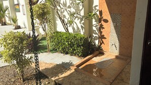 Une cour avec un patio carrelé, des plantes en pot et un mur orné d’un motif de carreaux.