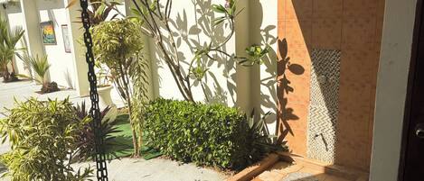 Un patio con suelo de baldosas, plantas en macetas y una pared con diseño de mosaico.