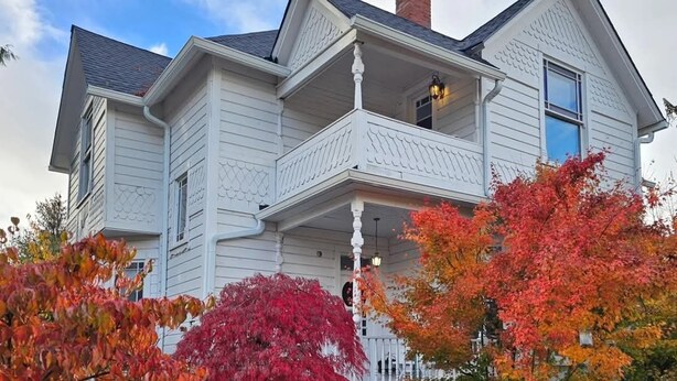 A two-story house with a porch and a chimney.