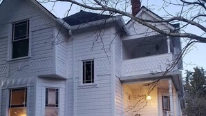 A two-story house with a front porch and a staircase leading to the entrance.